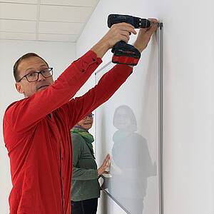 vhs-Mitarbeitende montieren Whiteboards im B3 Rottenburg